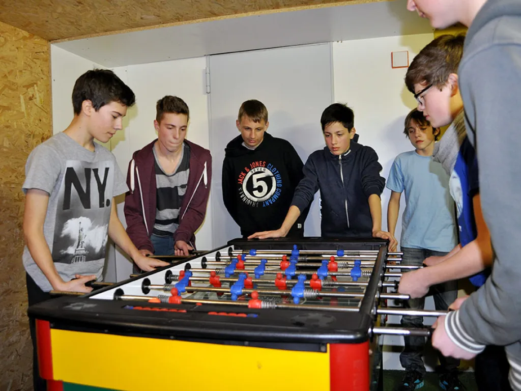 Jugendliche spielen im Aufenthaltsraum Tischfußball.